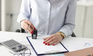Kobieta z czerwonymi paznokciami stempluje dokument. Obok kalkulator i wykresy. Sprawa spadkowa, do którego pokolenia szuka się spadkobierców?