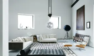 Soggiorno moderno con divani bianchi, chaise longue in pelle nera e un'iconica poltrona. Un ambiente che evoca case eleganti e raffinate.
