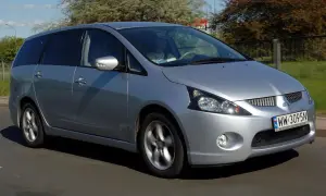 Srebrny Mitsubishi Grandis jedzie po drodze. Kierowca w jasnej koszulce prowadzi auto.