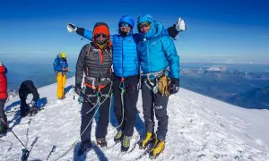 Drei Bergsteiger auf dem Gipfel des Monte Blanc, umgeben von Schnee und einer atemberaubenden Aussicht.
