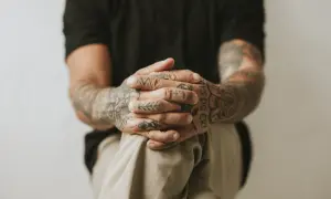 Dłonie z tatuażami wykonanymi metodą handpoke, z widocznym napisem "BOYS DO CRY".