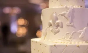 Biały tort weselny z ozdobami z masy cukrowej: lilie, kolibry i perełki.