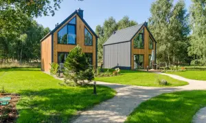 Nowe, nowoczesne domki w lesie nad morzem, otoczone zielenią i ścieżkami.