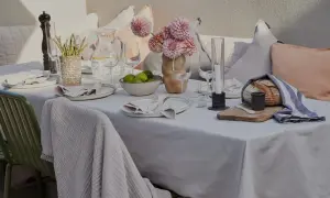 En vacker dukning utomhus med blommor, ljus och nybakat bröd. En inbjudande scen för en somrig middag.