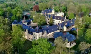 Zamek Kliczków z lotu ptaka, otoczony zielenią. Widać liczne skrzydła i wieżyczki, sugerujące bogactwo pokoi i historii.