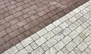 Pavimentazione esterna con blocchi di cemento color tortora e grigio chiaro, disposti a spina di pesce.