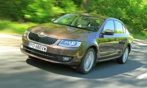 Brązowa Skoda Octavia jedzie po drodze wśród zieleni. Sprawdź aktualną skoda octavia cena!