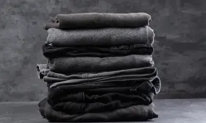 Stosik ciemnych ubrań, w tym jeansów z widocznymi odbarwieniami na jeansach po praniu.