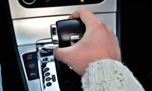 Dłoń trzymająca dźwignię zmiany biegów w samochodzie z napisem DSG. Widoczne przyciski ESP, Auto Hold i P.