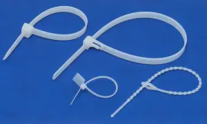 Białe trytytki o różnej długości i fakturze, gotowe do uporządkowania kabli lub innych przedmiotów.