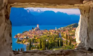 Vista incantevole del castello di Malcesine affacciato sul lago, con montagne sullo sfondo.
