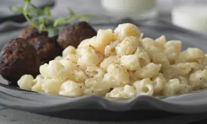 En portion stuvade makaroner snabbt vis med köttbullar och en kvist örter.