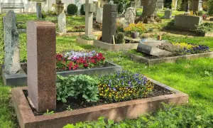 Cmentarz z zadbanymi nagrobkami i kwitnącymi kwiatami. Każdy grób to symbol prawa do grobu i pamięci.