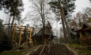 Kamienne schody prowadzą do drewnianej cerkwi na Grabarka Podlasie, otoczonej lasem i licznymi krzyżami.