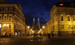 Wieczorne Gniezno: oświetlona ulica prowadzi do katedry, a budynki po bokach tworzą malowniczy widok. Atrakcje miasta nocą zachwycają.