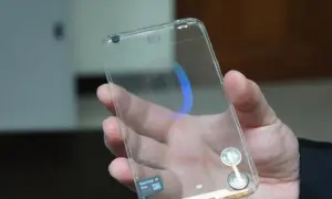 Dłoń trzyma przezroczysty telefon, który wygląda jak szklany. Widać w nim niebieski okrąg i kartę pamięci.