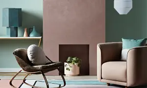 Simulazione abbinamento colori pareti: un salotto con poltrona in vimini, camino rosa e divano beige, su un tappeto geometrico.
