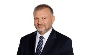Mężczyzna w garniturze i krawacie, z krótkimi włosami i zarostem. Wygląda jak prokurator generalny.