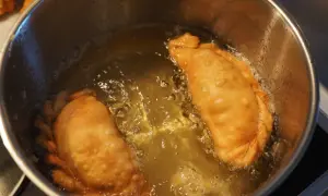 Due calzoni dorati friggono in olio bollente. Si puo friggere con olio d'oliva per un sapore autentico.