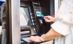 Kobieta dokonuje **revolut wypłata z bankomatu za granicą**. Wkłada kartę do bankomatu, by pobrać gotówkę.
