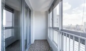 Nowoczesna zabudowa balkonu w bloku z dużymi oknami i widokiem na miasto.