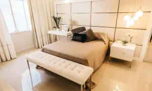 Elegancka sypialnia z tapicerowanym zagłówkiem, który pokazuje, jak zamontować panele tapicerowane na ścianie. Jasne kolory i minimalistyczne meble tworzą przytulną atmosferę.