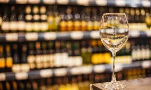 Verre à vin vide sur un comptoir, devant des étagères remplies de bouteilles. L'ambiance évoque une dégustation de vin à Paris.