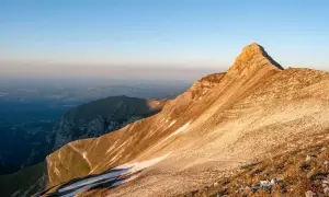Alba dorata sulla Sibilla Appenninica, con valli nebbiose e un rifugio solitario in vetta.