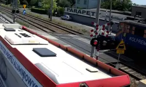 Autobus czeka na przejazd kolejowy w drodze do Częstochowy. Pociąg Kolprem mija przejazd.