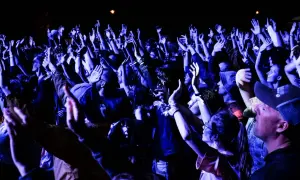 Tłum na koncercie z rękami w górze, zastanawiający się, dlaczego popularny zespół muzyczny nagle zawiesił działalność.