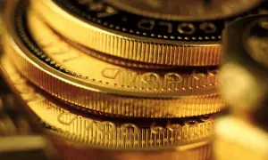 Zbliżenie na stos złotych monet z widocznym napisem "GOLD".