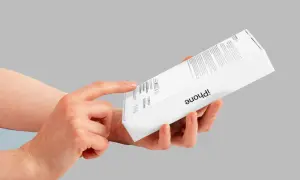 Dłoń wskazuje na pudełko iPhone'a, gdzie można znaleźć informacje, jak sprawdzić numer seryjny telefonu.