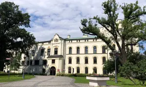 Zamek w Żywcu, okazała budowla z białymi ścianami i licznymi oknami, otoczony zielenią i starymi drzewami.