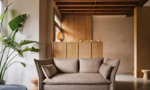 Gemütliches Wohnzimmer mit beigem Sofa, großer Zimmerpflanze und einem Schrank aus hellem Holz, der zum holz streichen einlädt.