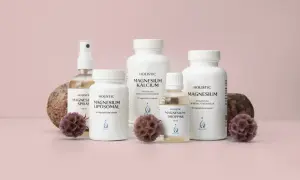 Flera flaskor och burkar med magnesiumtillskott, inklusive magnesium tillskott gravid, står uppradade med stenar och torkade blommor.