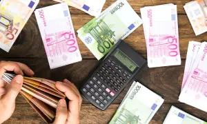 Ręce liczą banknoty euro. Obok kalkulator i stosy pieniędzy. Planowanie spadku dla obcej osoby i podatek od niego.