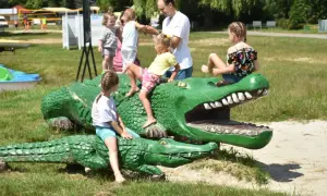 Dzieci bawią się na drewnianych krokodylach, które są jednymi z atrakcji dla dzieci w Okunince.