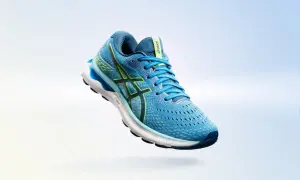 Scarpa da running Asics Gel Nimbus 24 uomo blu con dettagli gialli, in volo su sfondo sfumato.