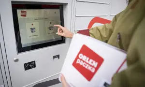 Kobieta z paczką ORLEN PACZKA dotyka ekranu automatu, wybierając opcję nadania przesyłki.