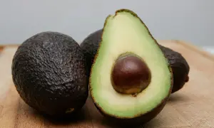 Dwa całe awokado i jedno przekrojone na pół, z widocznym pestką. Idealne do zdrowej diety, choć awokado kcal warto znać.