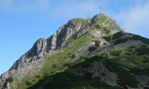 Szczyt Giewontu z krzyżem, symbol Tatr. Widok na skaliste zbocza i zielone hale, które góry są w Zakopanem.