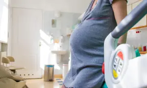 Gravid kvinna i sjukhusklänning, redo för förlossning. Knipkulor kan vara en del av förberedelserna.