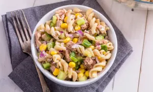 Ein köstlicher nudelsalat mit thunfisch, garniert mit Mais, Gurken und roten Zwiebeln, bereit zum Genießen.