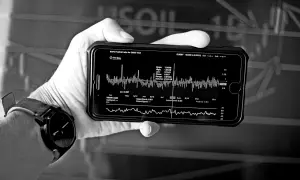 Dłoń trzyma smartfon z wykresem finansowym, analizującym strategię DCA. Widoczne dane rynkowe i wskaźniki.