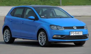 Niebieski VW Polo 2010 z czarnym dachem, zaparkowany na zewnątrz. Kierowca siedzi za kierownicą.