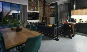 Nowoczesny salon z jadalnią i aneksem kuchennym. Wygodna kanapa, kominek, duży stół. Zastanawiasz się, ile kosztuje wykończenie mieszkania w takim stylu?