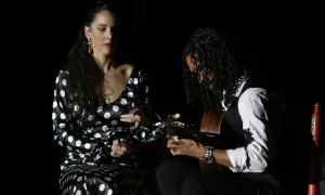 Unos buenos días flamencos con una bailaora y un guitarrista en un escenario oscuro.