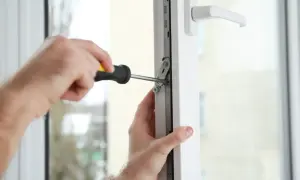 Regulacja drzwi balkonowych uchylnych. Ręce majsterkowicza dokręcają śrubę w mechanizmie okna.