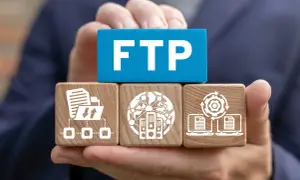 Dłonie trzymają kostki symbolizujące połączenie FTP: transfer plików, serwery w sieci i synchronizację danych.
