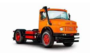 Un gros camion américain orange vif, prêt pour l'aventure, avec un échappement sur le côté.